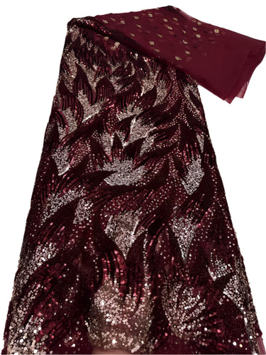 Sequined fabric with a leaf pattern in red and gold on a white surface