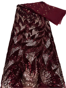 Sequined fabric with a leaf pattern in red and gold on a white surface